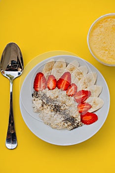 Bowl of breakfast muesli decorated with banana, strawberry slices and chia seed, top view