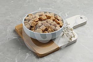 Bowl of brown sugar cubes on light grey marble table