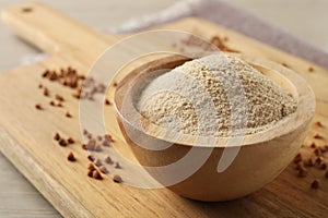Bowl of buckwheat flour on white wooden table, closeup. Space for text