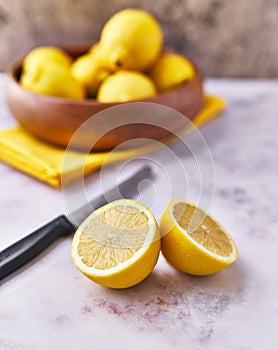 Bowl of bunch of lemons and halves on a marble surface