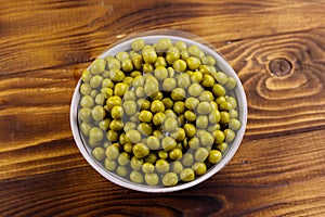 Bowl with canned green peas  on wooden table. Top view