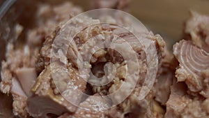 Bowl with canned tuna chunks on a wooden tray table. 4K video. Artistic shooting, slowmotion