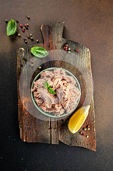 Bowl with canned Tuna on a wooden board. Food recipe background. Close up