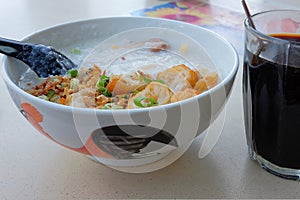 A bowl of Cantonese Ting Zai porridge or congee with a cup of traditional Nanyang black coffee for breakfast