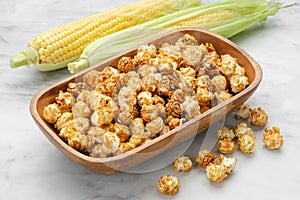Bowl of caramel popcorn, fresh corncobs on background
