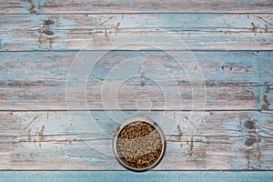 Bowl with cat kibble seen from above on blue scaffolding plank floor