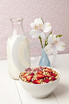 Bowl of cereal with strawberries with bottle of milk