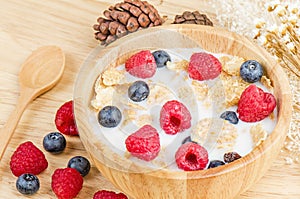 Bowl of cereals with raspberries and blueberrys on a wooden