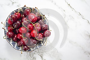 Bowl with cherries on marble background Top view with copy space