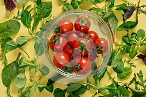 A bowl of cherry tomatoes with green leaves natural food on a table