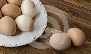 Bowl of chicken eggs, wooden background.