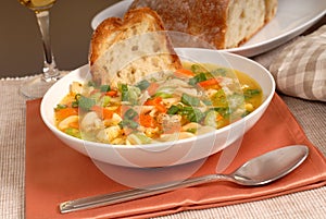 Bowl of chicken noodle soup with rustic bread and a glass of win
