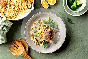 Bowl with chicken, pasta orzo with vegetables in Mediterranean style on a green background.