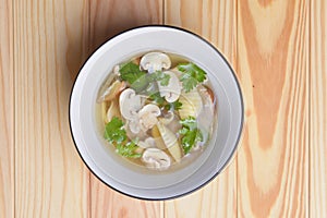 Bowl of chiken broth mushroom soup with mushrooms and macaroni served in a white bowl over rustic wooden table