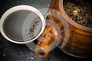 Bowl of Chinese herbal tea and an enamel pot with herbs