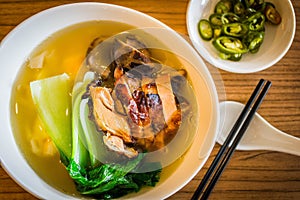 A bowl of chinese wanton noodle soup with chicken char siew and vegeatable on top