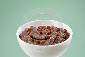 Bowl with chocolate balls. dry breakfast. crunchy corn balls with cocoa on color background.