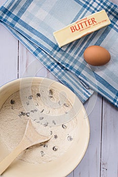 A bowl of chocolate chip cookie mix, stick of butter and an egg