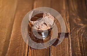 bowl of chocolate ice cream scoops with pieces of chocolate bar and waffle cones on dark background