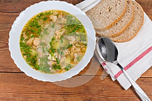 Bowl of clear salmon soup, bread, spoon on napkin