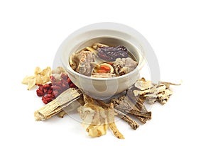 Bowl of clear soup around with  many chinese herbal medicine on white background