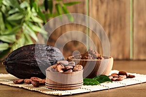 Bowl of cocoa beans, pod and powder on table, space for