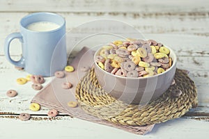 Bowl of colorful cereals with a glass of milk