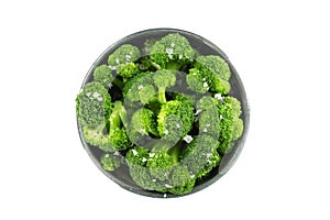 A bowl of cooked broccoli, isolated on a white background with a clipping path, shot from above