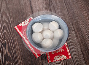 A bowl of cooked dumplings and red envelopes