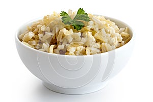 Bowl of cooked long grain brown rice with green parsley isolated