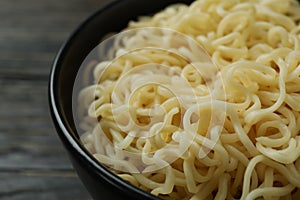 Bowl with cooked noodles on wooden background, close up