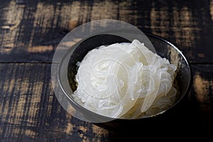 Bowl of cooked rice noodles on wood table