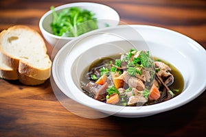 bowl of coq au vin garnished with parsley, side of crusty bread