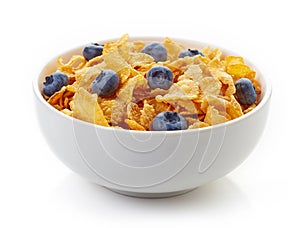 Bowl of corn flakes and blueberries isolated on white