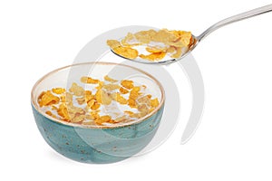 Bowl of corn flakes with milk and spoon isolated on white