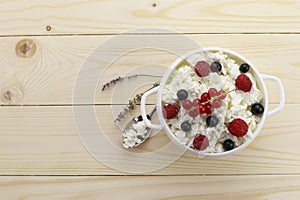 Bowl with cottage cheese and fresh berries on wooden table