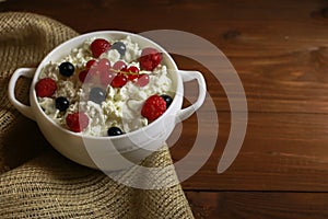 Bowl with cottage cheese and fresh berries on wooden table