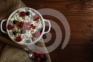 Bowl with cottage cheese and fresh berries on wooden table