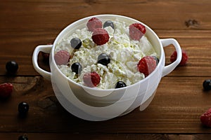 Bowl with cottage cheese and fresh berries on wooden table