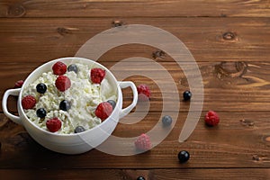 Bowl with cottage cheese and fresh berries on wooden table