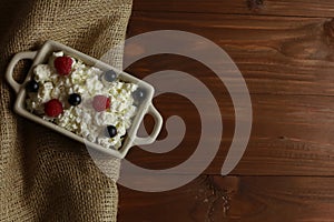 Bowl with cottage cheese and fresh berries on wooden table