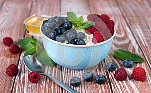 A bowl with cottage cheese, ripe berries and honey on the wooden table. Healthy breakfast in the morning. ?lose-up