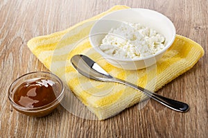 Bowl with cottage cheese, spoon on napkin, bowl with boiled condensed milk on table