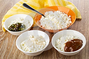Bowl with cottage cheese, spoon, napkin, bowls with cottage cheese, gooseberry jam, milk on table