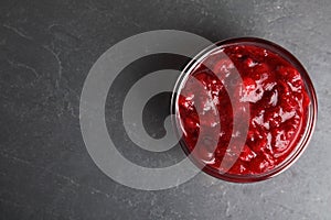 Bowl of cranberry sauce on grey background, top view.