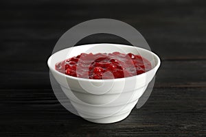Bowl of cranberry sauce on wooden background
