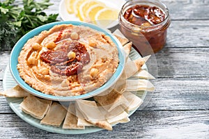 A bowl of creamy homemade hummus with with sun-dried tomatoes, olive oil and pita chips. traditional vegan healthy meal