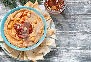 A bowl of creamy homemade hummus with with sun-dried tomatoes, olive oil and pita chips. traditional vegan healthy meal