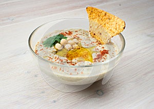 A bowl of creamy hummus with olive oil and chips.