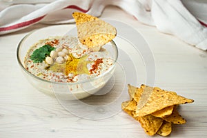 A bowl of creamy hummus with olive oil and chips.